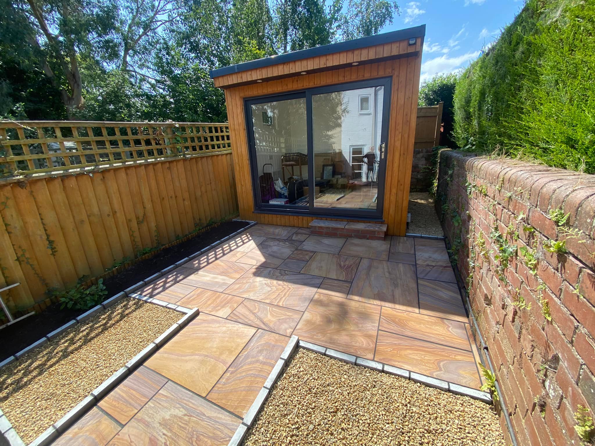 Sandstone patio with a garden room and gravel